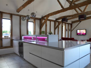 Sleek handle-less kitchen with pink splash-back ensures a modern contemporary look in this barn conversion., John Ladbury and Company John Ladbury and Company Nhà bếp phong cách hiện đại