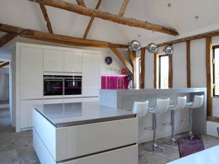 Sleek handle-less kitchen with pink splash-back ensures a modern contemporary look in this barn conversion., John Ladbury and Company John Ladbury and Company Кухня в стиле модерн