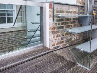 Painted mild steel construction open string-riser access staircase to the rear garden patio with glass balustrades., Railing London Ltd Railing London Ltd Modern Garden