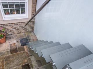 Painted mild steel construction open string-riser access staircase to the rear garden patio with glass balustrades., Railing London Ltd Railing London Ltd Moderne tuinen