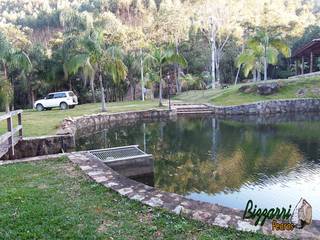 Muro de pedra em volta do lago com a cabana rústica, Bizzarri Pedras Bizzarri Pedras Rustic style gardens Stone