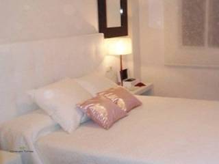 Dormitorio en blanco homify Dormitorios tropicales Cuero sintético Metálico/Plateado Camas y cabeceras