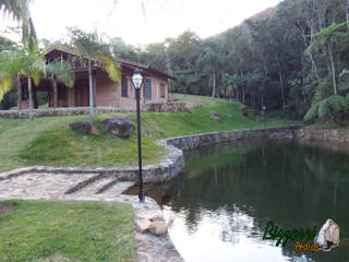 Ao lado da cabana a construção do lago com pedras, Bizzarri Pedras Bizzarri Pedras Tropical style garden