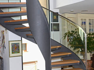 Moderne Wendeltreppe mit Glasgeländer auf Betonsockel, MetallArt Treppen GmbH MetallArt Treppen GmbH Vestíbulos, pasillos y escalerasEscaleras