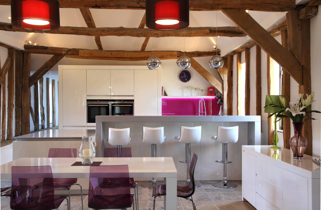 Sleek handle-less kitchen with pink splash-back ensures a modern contemporary look in this barn conversion., John Ladbury and Company John Ladbury and Company Modern kitchen