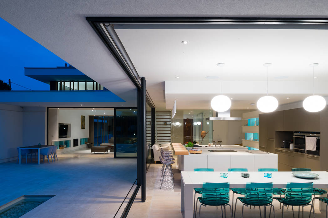 River House - Internal/external night view of dining room and kitchen Selencky///Parsons Salas de jantar modernas