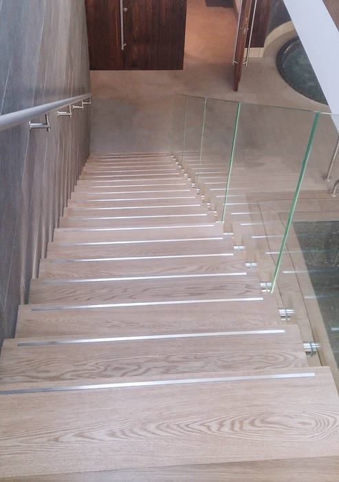 A custom-made floating staircase with oak-clad treads, a clear-glass balustrade and a wall-mounted stainless steel handrail. Railing London Ltd Pool