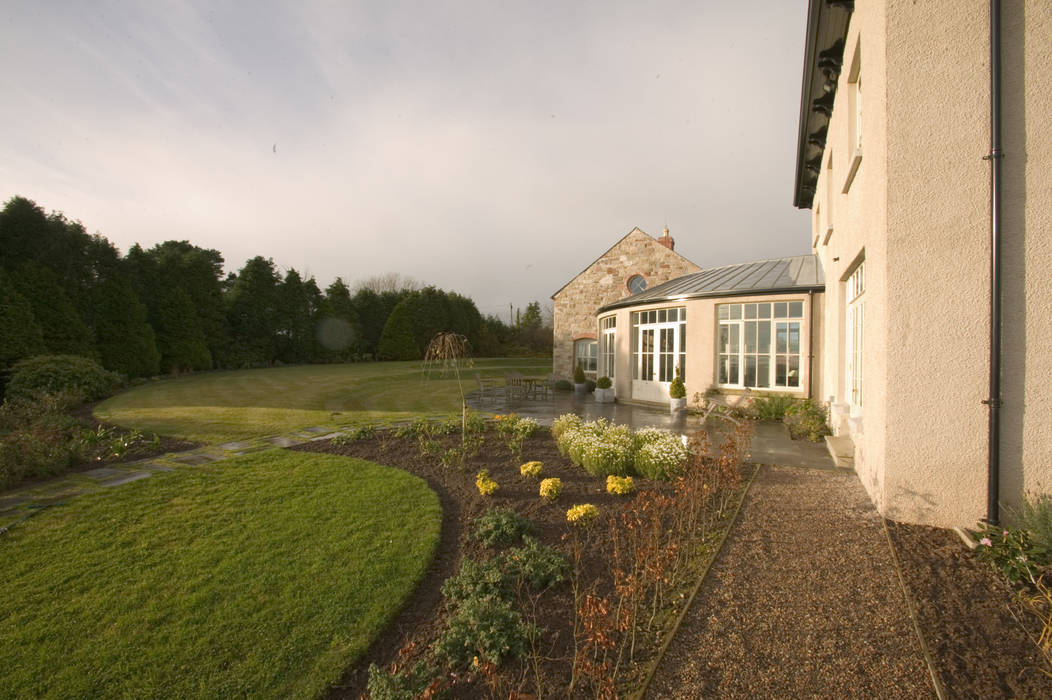 Lime render finish provides a soft natural tone to this new country house set on top of a drumlin, Des Ewing Residential Architects Des Ewing Residential Architects Jardins clássicos