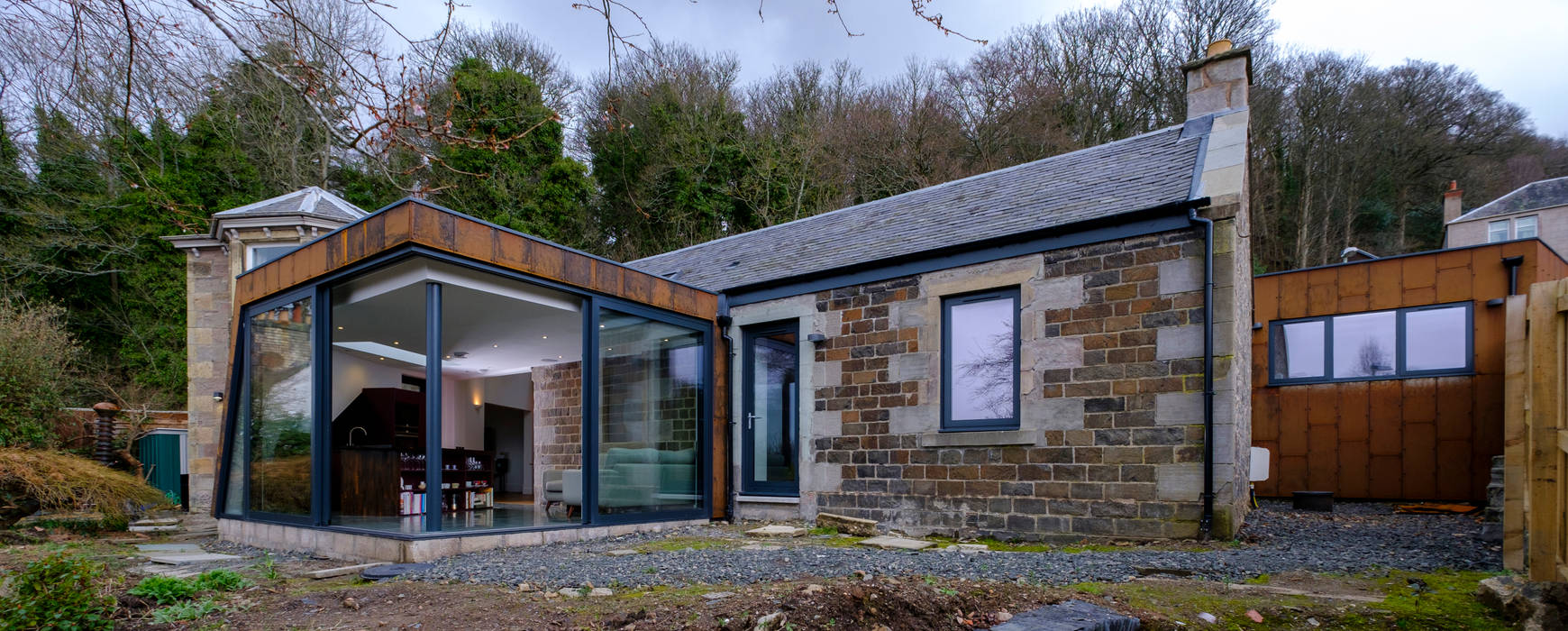 The rear extension to Woodend Cottage is clad in Corten steel and features large glass sliding doors Woodside Parker Kirk Architects Modern Evler Demir/Çelik Corten steel,cladding,cottage,extension,flat roof,alu-clad windows,daylight,garden