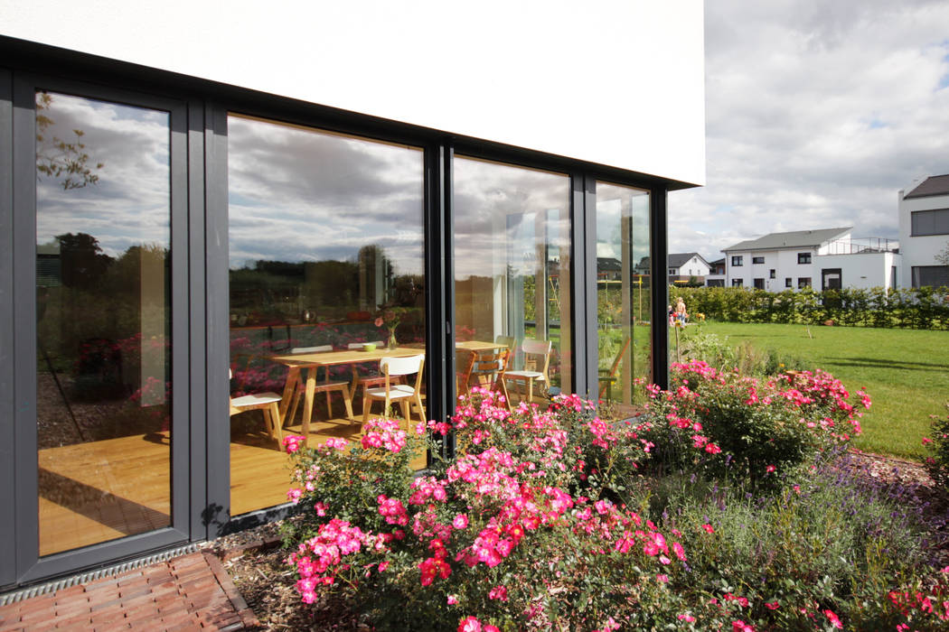 Eckfenster Rosenbeet ARCHITEKTEN BRÜNING REIN Moderne Fenster & Türen Blumenbeet,bodentiefe Fenster,großzügige Öffnung,hell,kompakter Baukörper,Kontrast,offener Wohnraum,Passivhaus,Rosengarten,Sonnenlicht,Terrasse