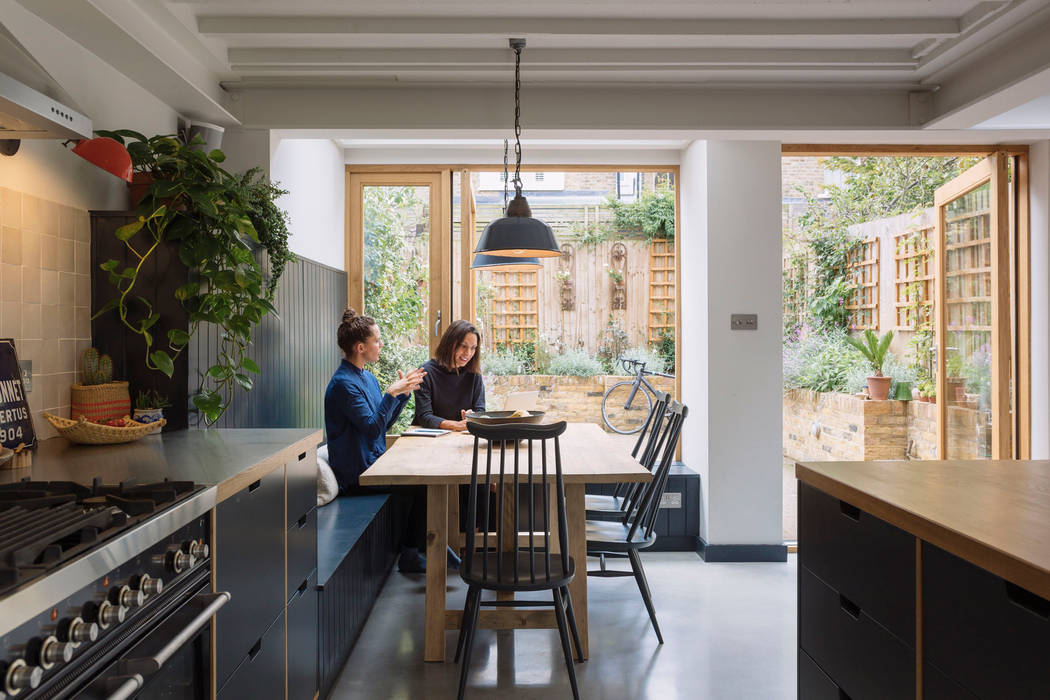 Dining space with view through to garden Mustard Architects Comedores eclécticos dining,kitchen dining,oak table,spindle chairs,timber panelling,concrete flooring,oak kitchen,exposed joists,industrial light,rooflight,skylight