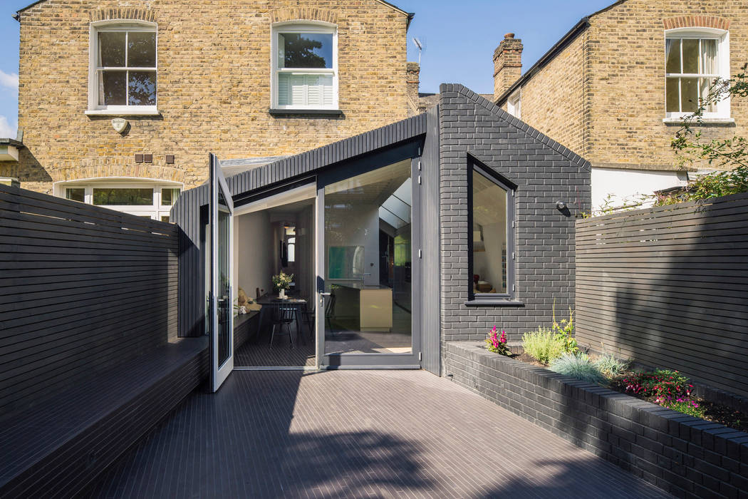 External view Mustard Architects Terrace house brick,angle,angled roof,pitched roof,black brick,raised planters,angled doors,black timber,vertical timber,timber battens,timber cladding