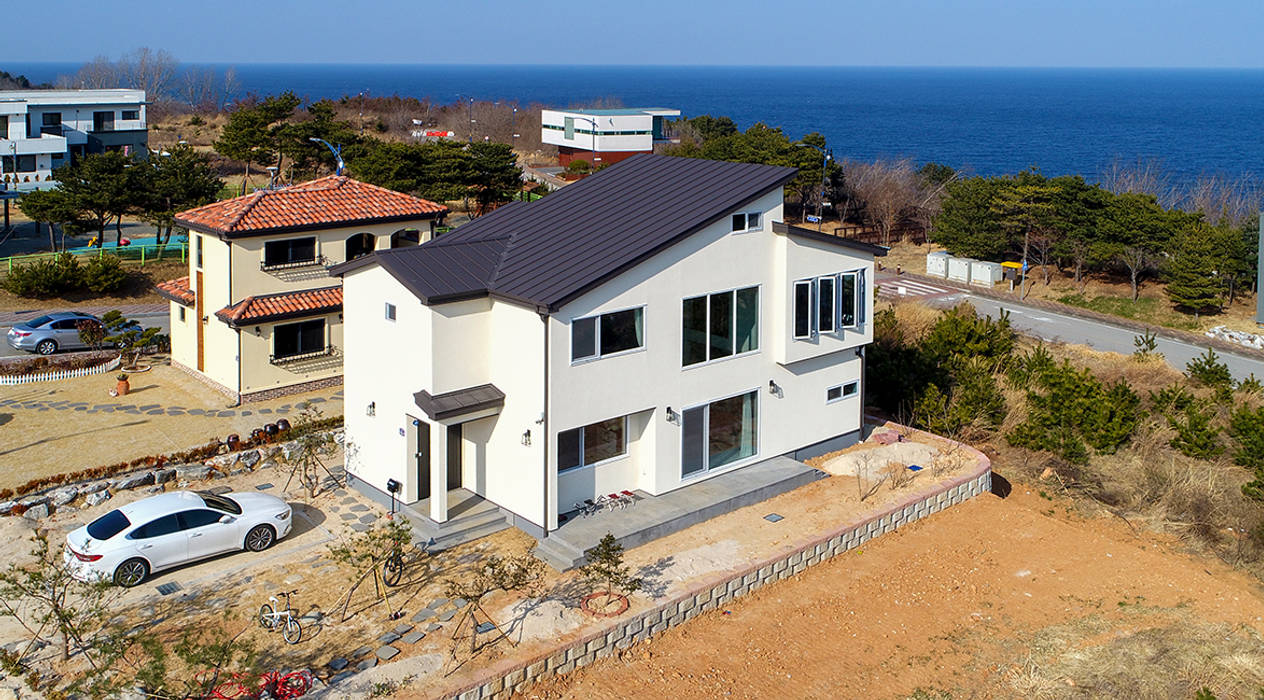 바다위 환하게 빛나고 있는 하얀집 , 더존하우징 더존하우징 Casas de campo