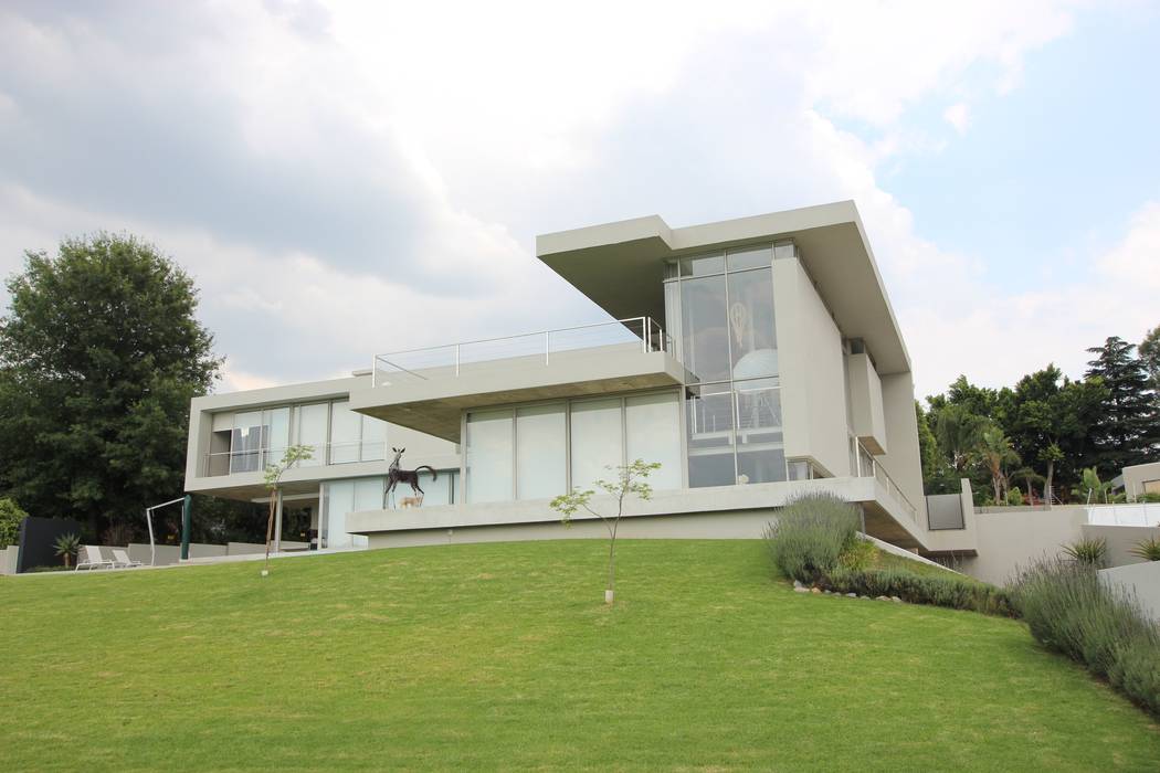 View of the west facade overlooking the rolling sloping lawn of the garden. Internal sun screen blinds shiled against the west sun in the late afternoon Green Evolution Architecture Single family home Reinforced concrete modern minimalist architecture