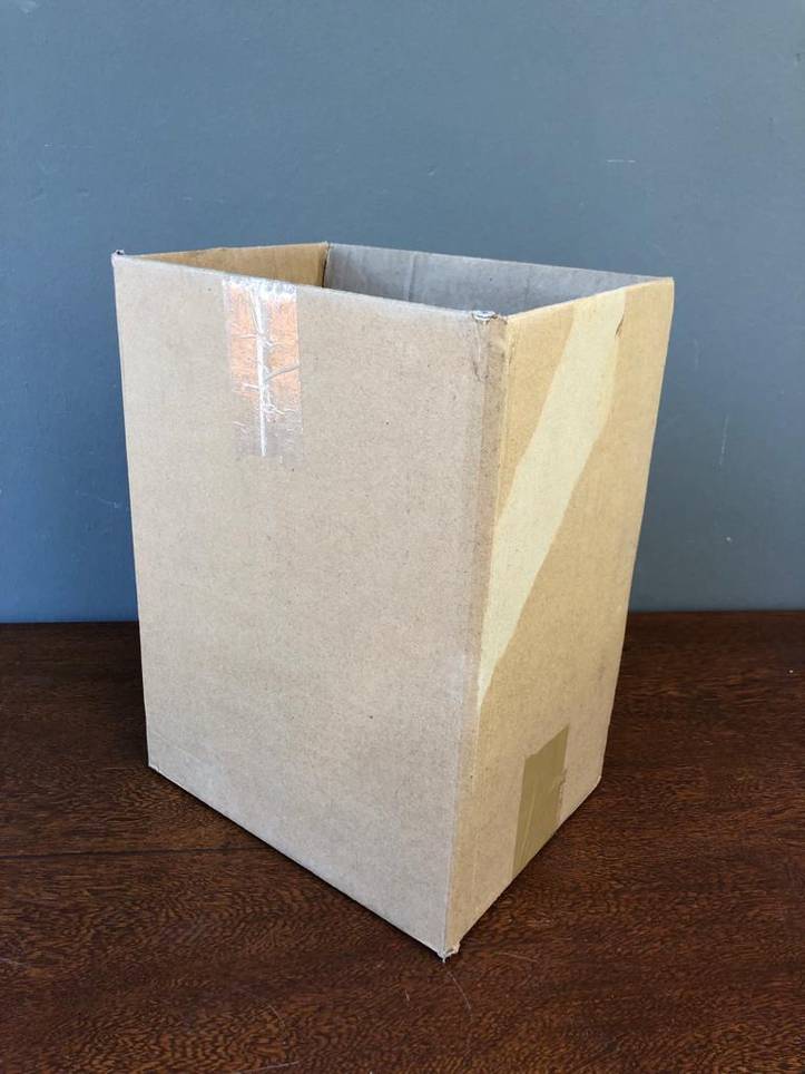 Homemade trashcan made of a cardboard box with plastic bag in it