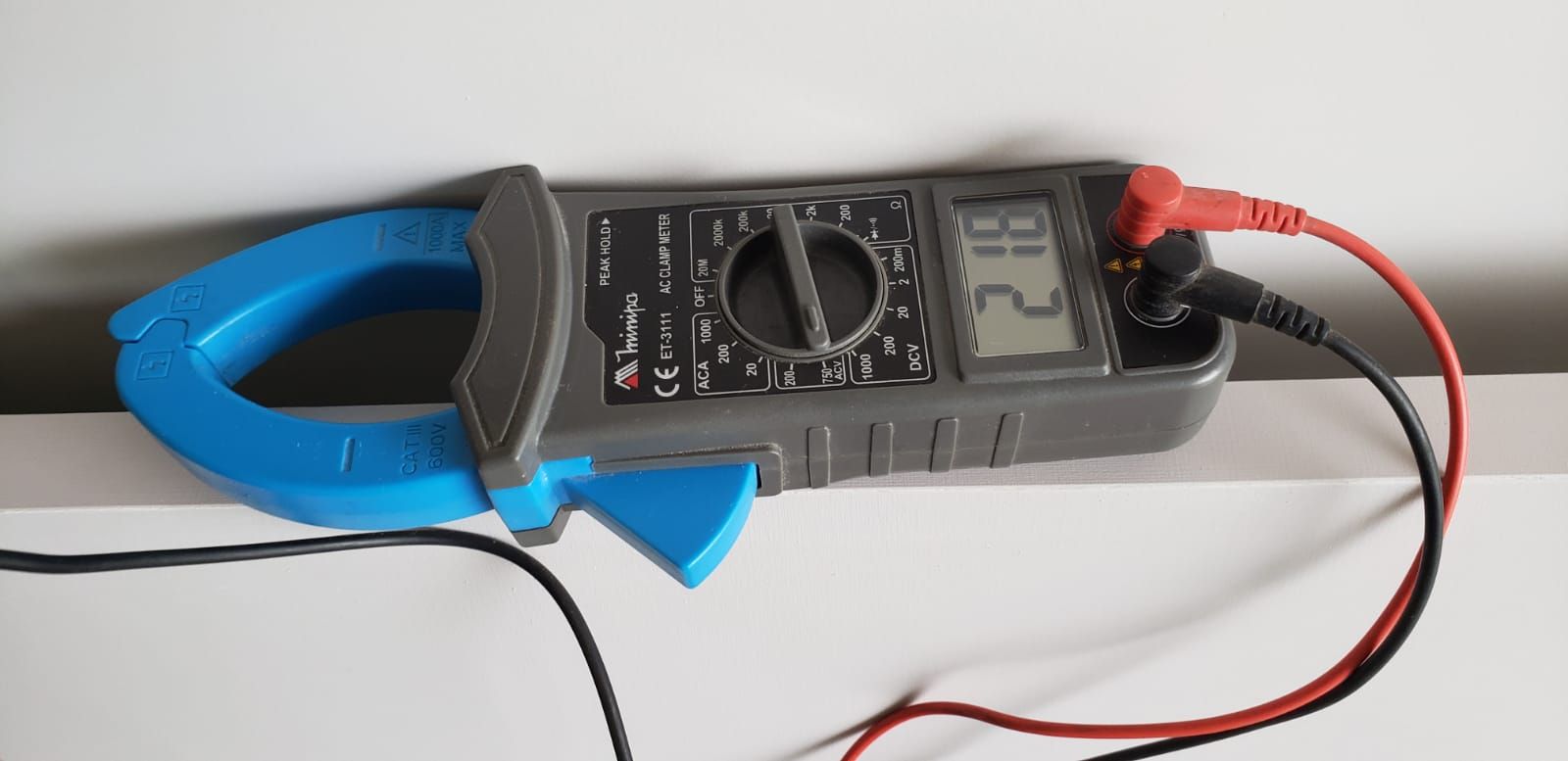 Misurazione della tensione tramite tester. multimetro digitale nel foro  della presa elettrica. servizio elettricista.