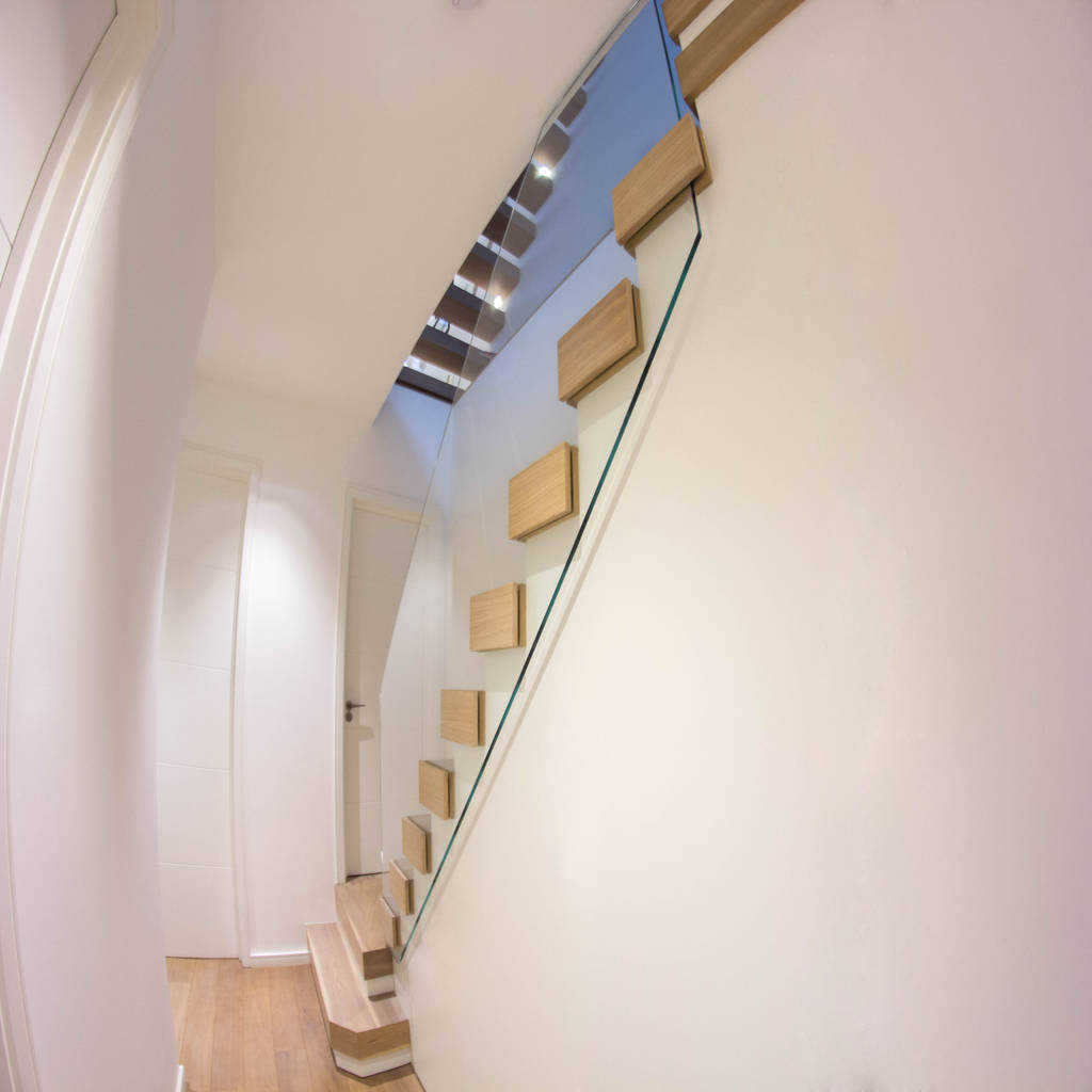 A minimalist floating staircase with oakclad treads and glass wall