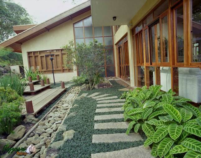 Caminho com pedras no jardim com canaleta de pedra e os seixos de