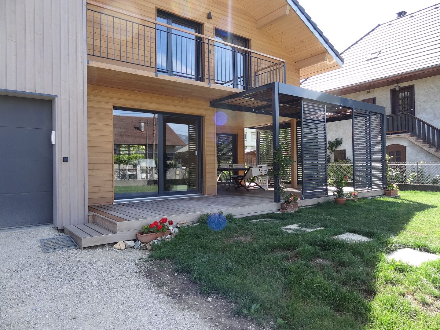 Vue de la façade principale et de la terrasse ombragée Tangentes Architectes Maisons modernes