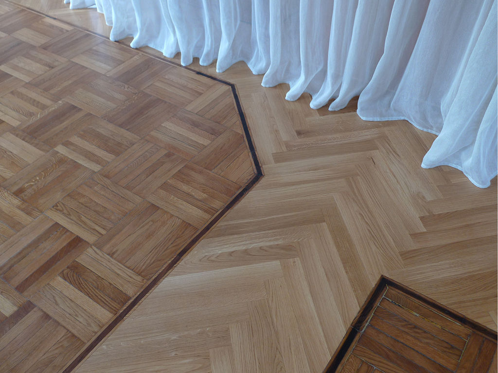 Gli inserti del nuovo parquet in rovere a spina di pesce interagiscono con quello preesistente Forestieri Pace Pezzani Pareti & Pavimenti in stile moderno