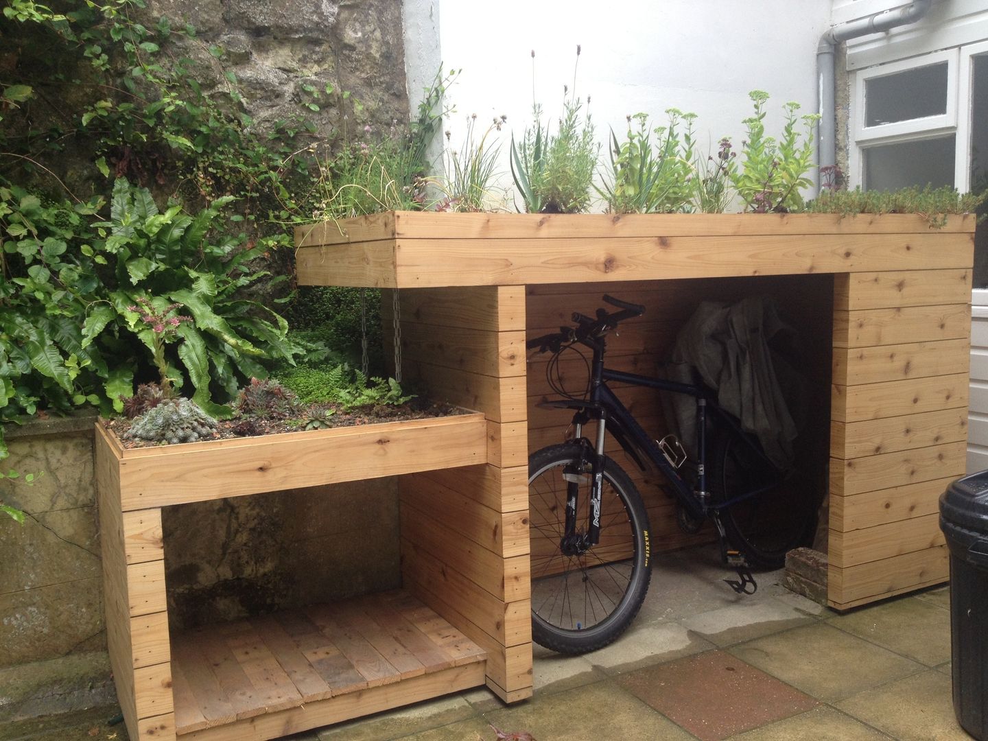 Bike and log store with green roof Organic Roofs Jardines de estilo moderno