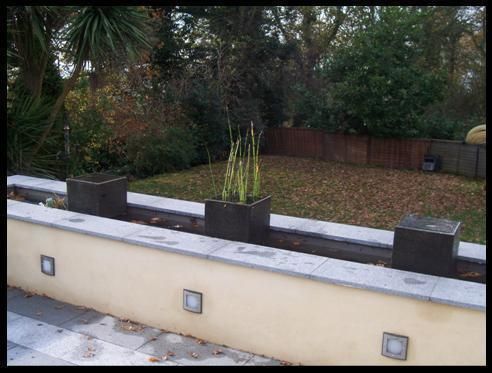 Long water feature with simple planted pots Westacott Gardens