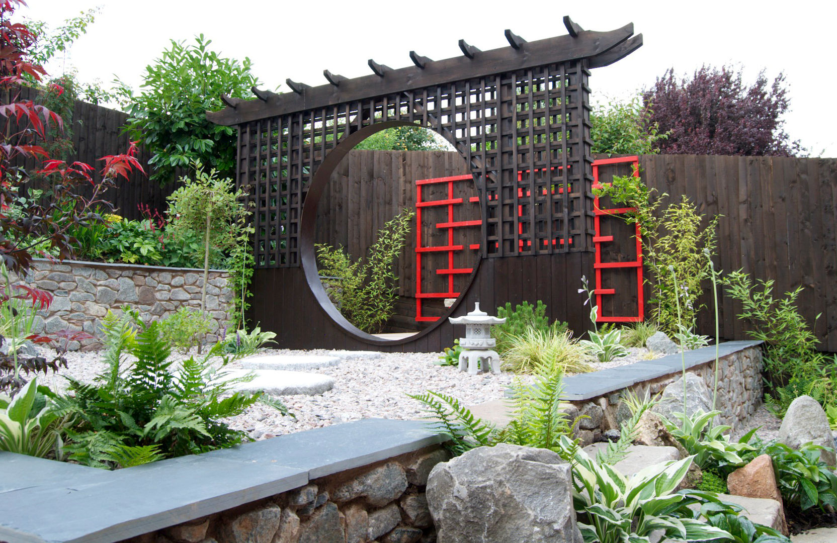 The moon gate with wooden art behind Lush Garden Design Azjatycki ogród