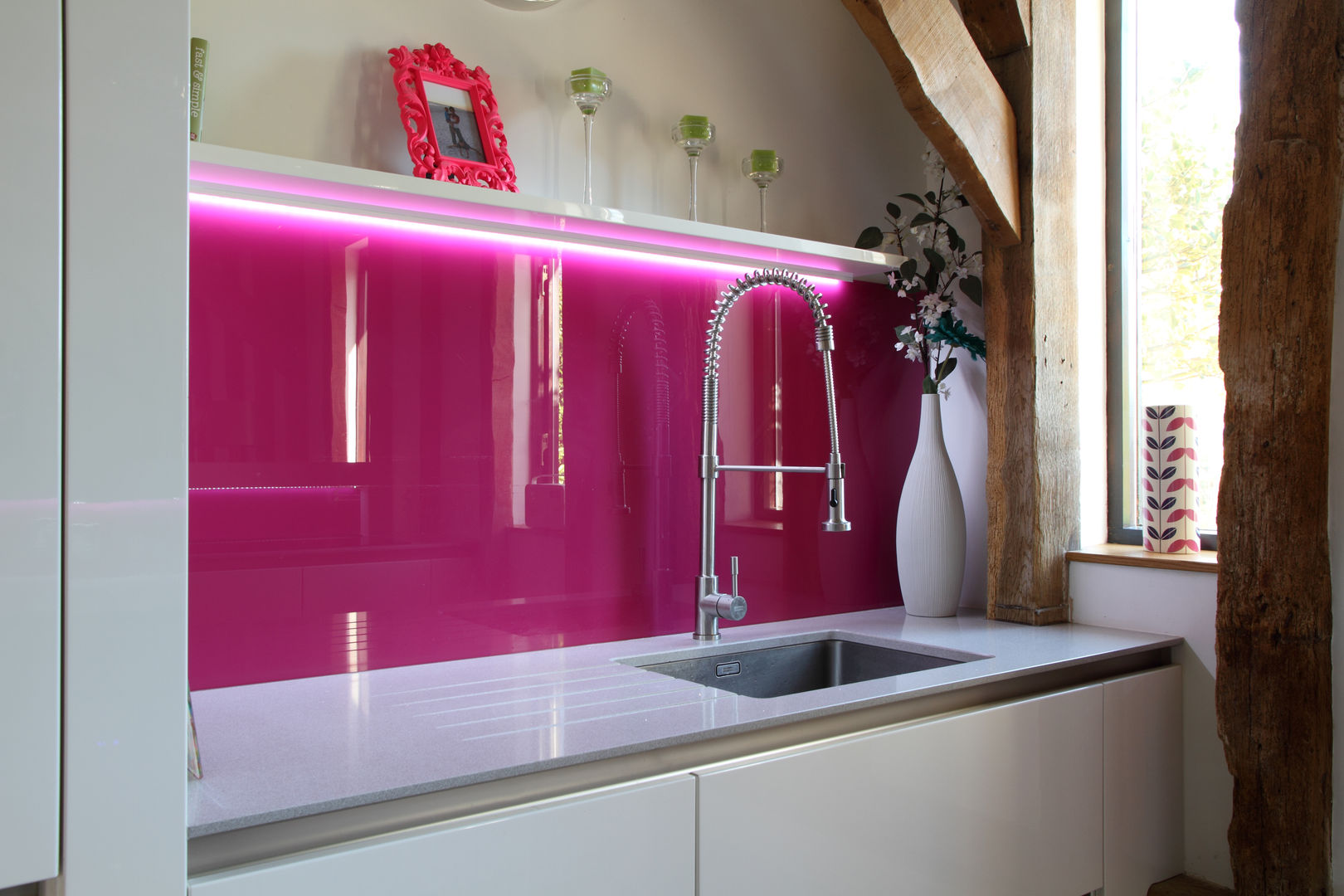 Sleek handle-less kitchen with pink splash-back ensures a modern contemporary look in this barn conversion., John Ladbury and Company John Ladbury and Company مطبخ