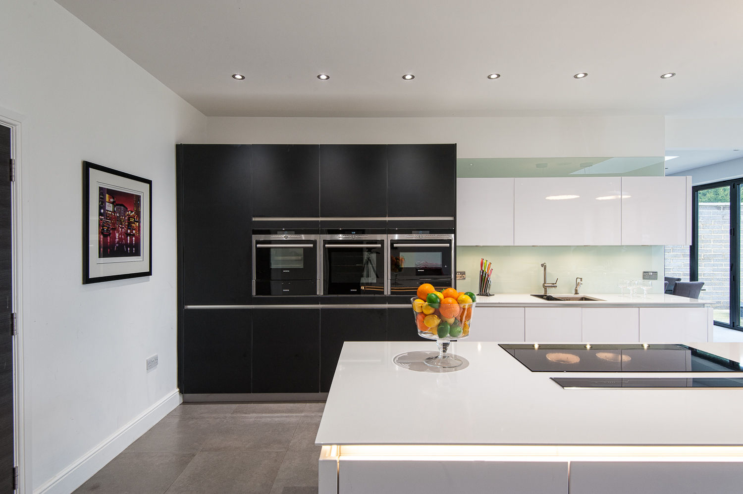 Urban Style Kitchen - White handle-less kitchen with satin black glass units homify Cocinas modernas