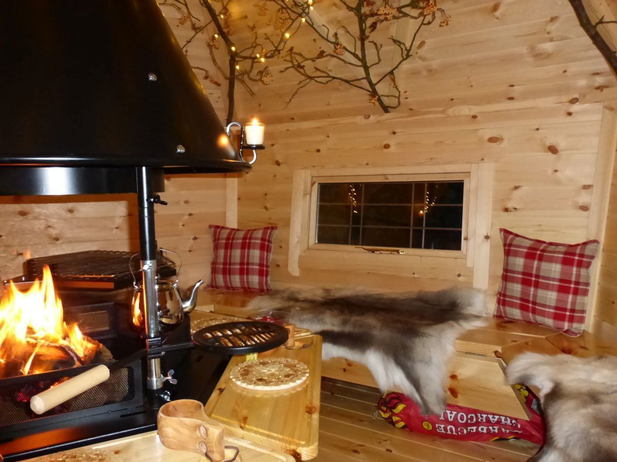 The interior of a 10m² cabin, fire going lovely cushions and reindeer skins on the benches. Arctic Cabins Сад