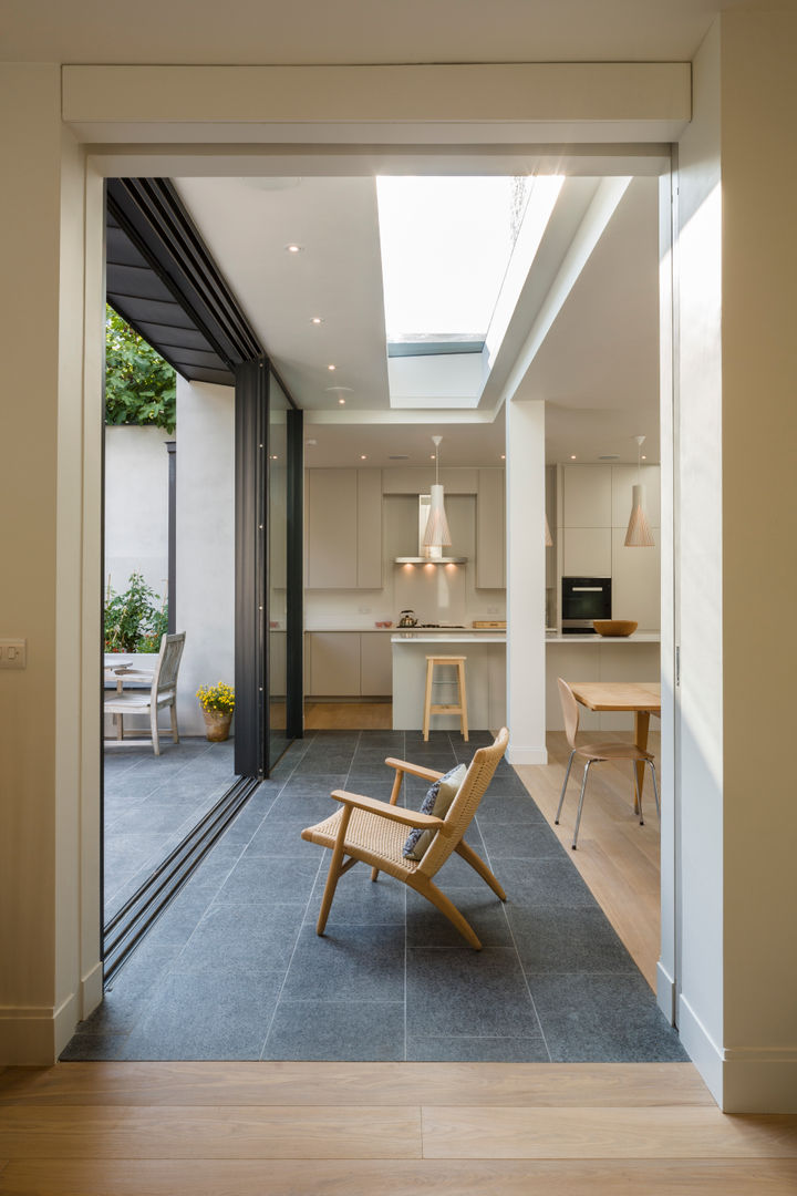 Kitchen/dining room in North London house extension, viewed from the adjacent sitting room. Jones Associates Architects Cocinas modernas house extension, house refurbishment, modern extension, contemporary extension, house renovation, rear extension, roof extension, 1930s house, North London house extension, North London house refurbishment, Crouch End house extension, Crouch End house refurbishment, Crouch End house renovation, Crouch End house alterations, Crouch End architect, Muswell Hill house extension, Muswell Hill house refurbishment, Muswell Hill house renovation, Muswell Hill house alterations, Muswell Hill architect, N10 house extension, N10 house refurbishment, N10 house renovation, N10 house alterations, N10 architect, modern kitchen, contemporary kitchen, kitchen dining room, kitchen island, sliding glass doors, rooflight, pocket door