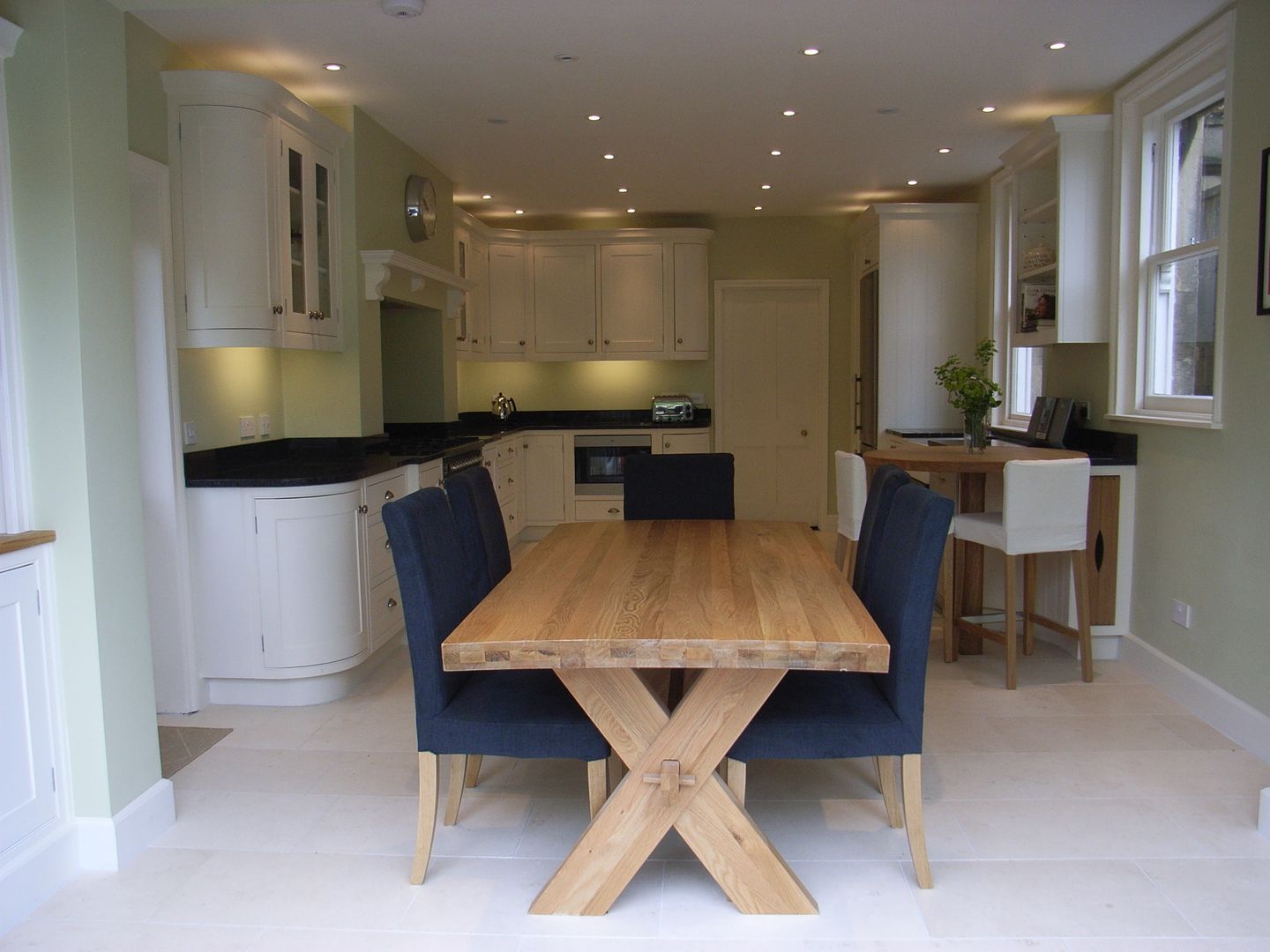 Dining end of kitchen diner Style Within Cozinhas clássicas Madeira Acabamento em madeira garden room,open plan,kitchen diner,granite worktop,white kitchen,classic kitchen,travertine floor,curved base unit,black worktop,kitchen lighting,oak dining table