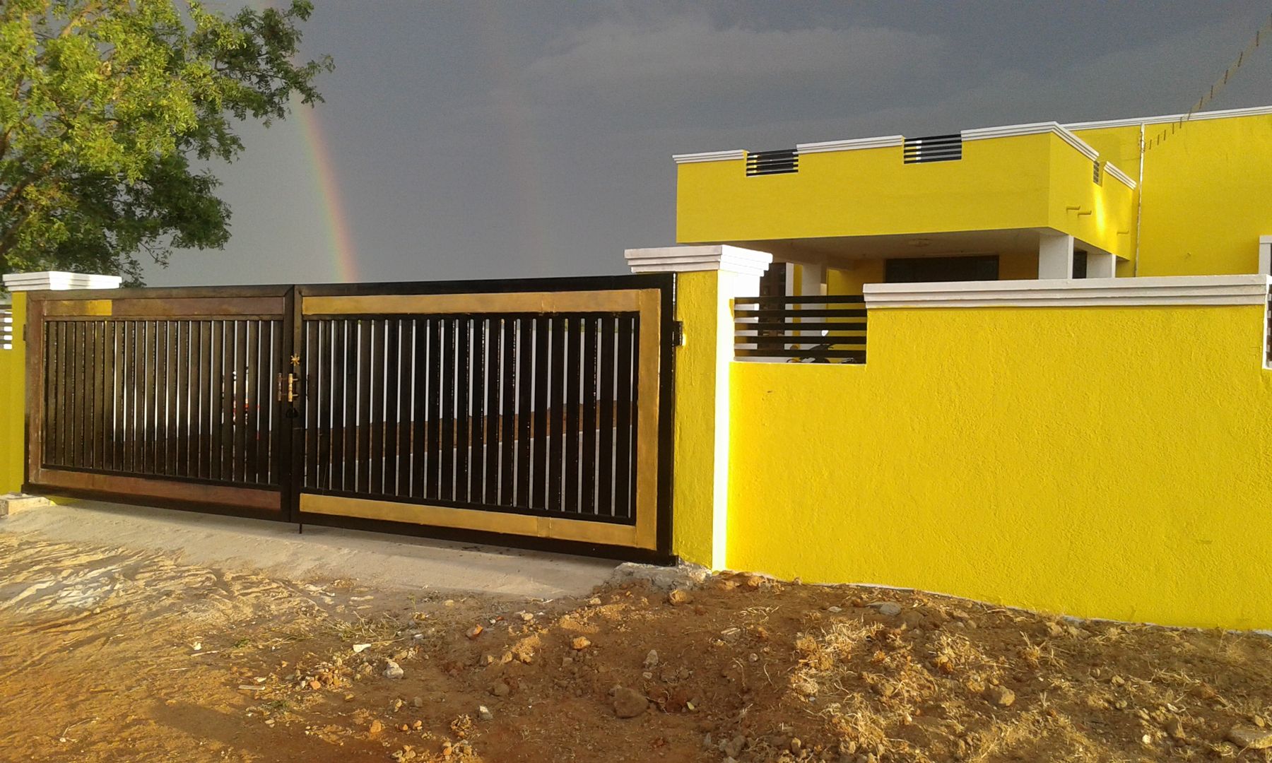 Entrance gate NISHA MIDAS CONSTRUCTION Tropical style windows & doors Iron/Steel Rainbow,Cloud,Sky,Tree,Water,Architecture,Shade,Sunlight,Road surface,Yellow