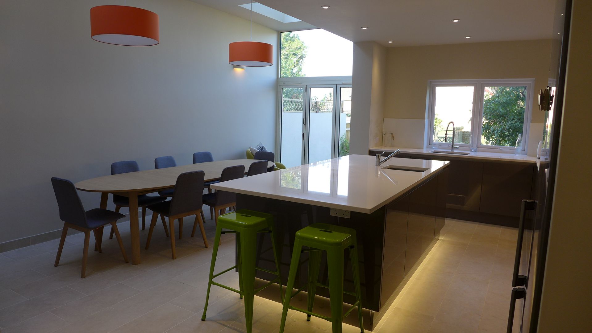 Gloss grey kitchen island in side return extension Style Within Modern Kitchen side return,extension,powder coated aluminium,bifold doors,glazed extension,gloss grey kitchen,white worktop,white splashback,plinth light,kitchen island,glass facade