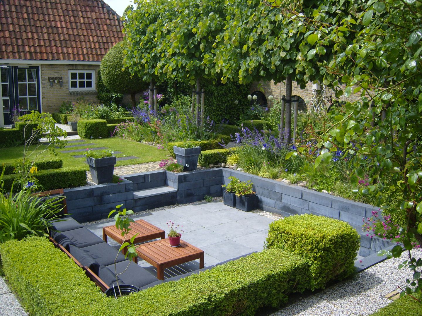 Moderne zitkuil in eigen tuin van tuinontwerper Joke Gerritsma, Joke Gerritsma Tuinontwerpen Joke Gerritsma Tuinontwerpen Modern style gardens Tiles