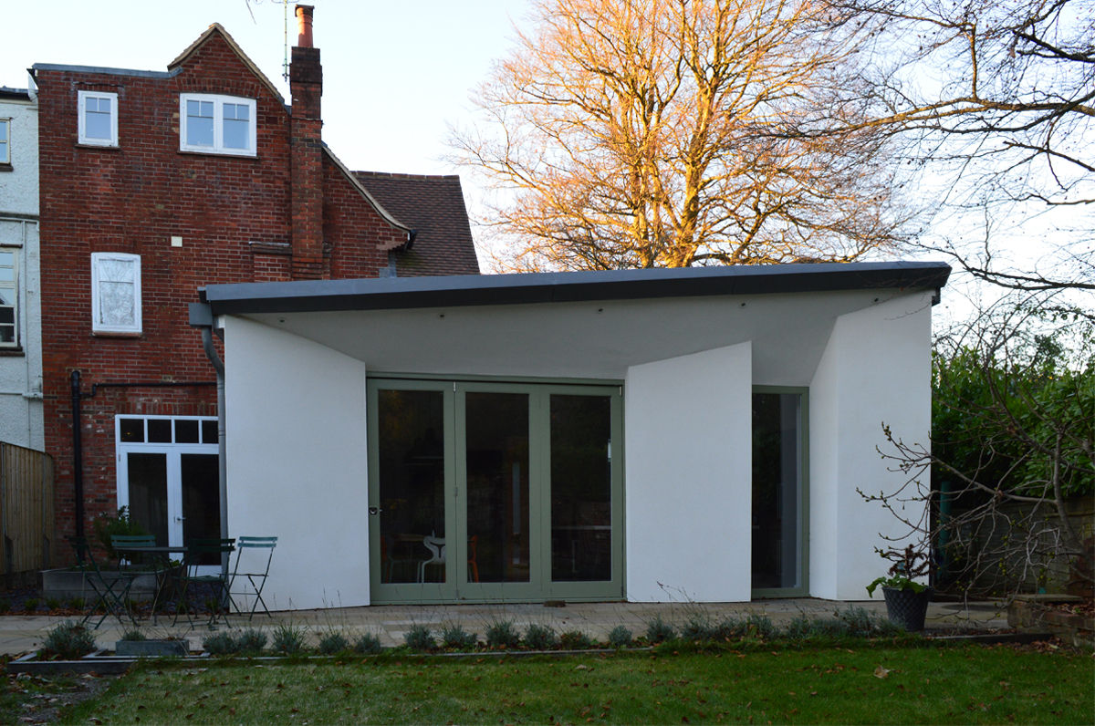 Rear view of the new single storey extension ArchitectureLIVE Modern houses extension,courtyard extension,single storey,green window frame,bifold doors,white render,zinc roof,butterfly roof,full height windows,patio