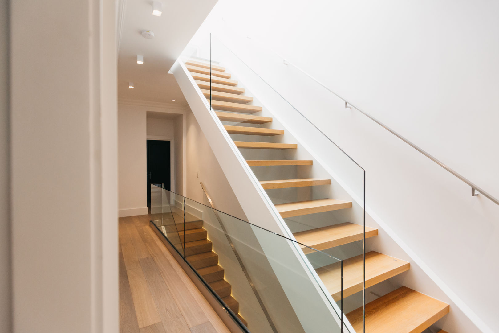 Beautiful wood stairs with glass panel railing FLUID LIVING STUDIO Modern corridor, hallway & stairs