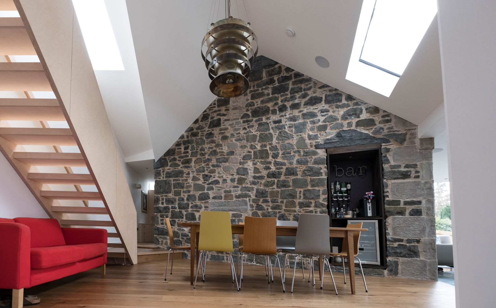 Dining room with exposed stone wall Woodside Parker Kirk Architects Столовая комната в стиле модерн Stone,Dining table,Bespoke,Bespoke Staircase,Plywood,Red sofa,Bar,Beer fridge,Rooflight,Daylight,Pendant light,Reclaimed