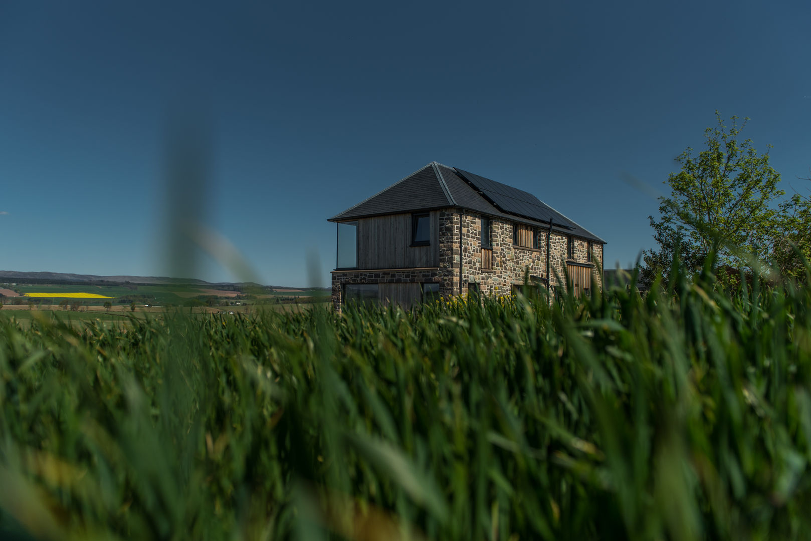 The house sits in its rural landscape like the former steading would have Woodside Parker Kirk Architects Rustic style house Farm steading,development,Stone,Timber,Glass corner,Glass to glass,solar cells,Renewables