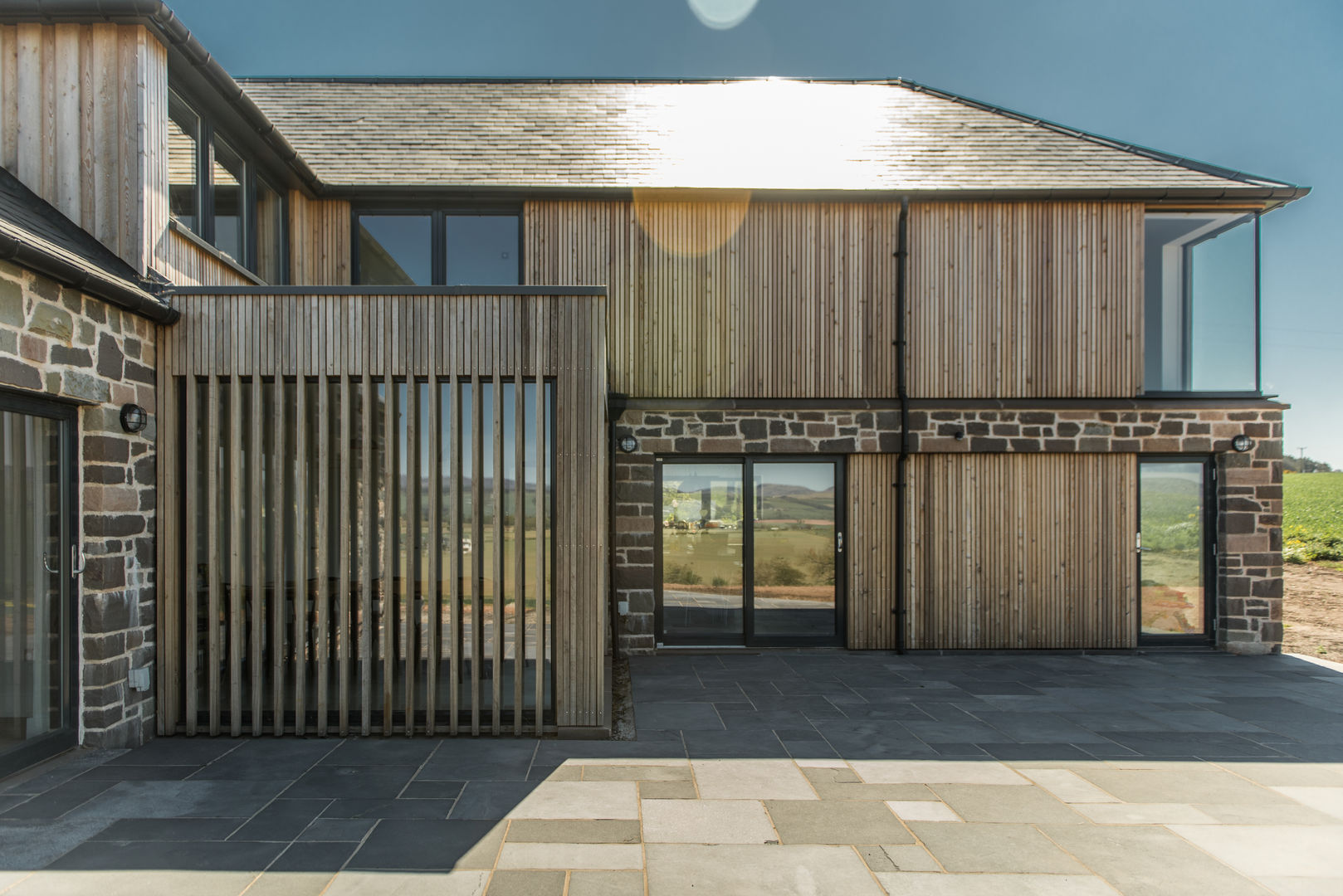 Timber and stone clad balances modern and traditional Woodside Parker Kirk Architects Balcone, Veranda & Terrazza in stile rustico Timber,cladding,battens,patio,Stone house,Rural design,Farm steading,development