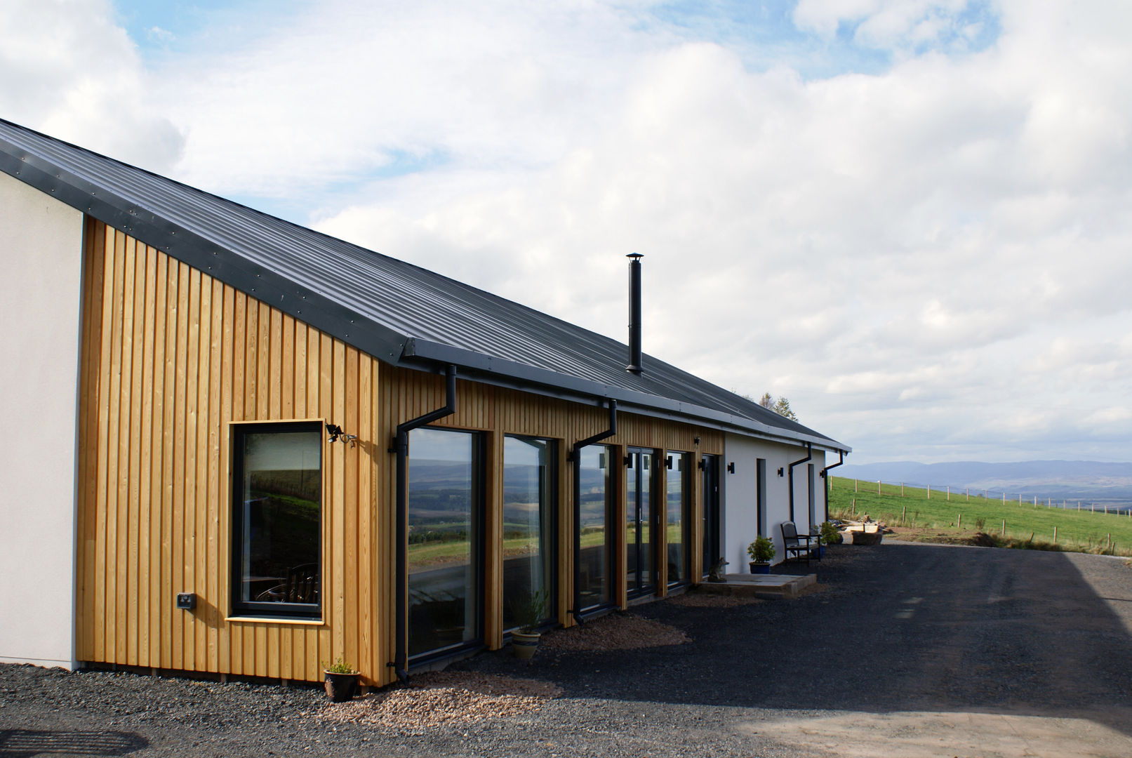 Large windows capture daylight and the views Woodside Parker Kirk Architects Casas modernas metal roof,timber cladding,render,chimney,alu-clad windows,view,daylight,,landscape