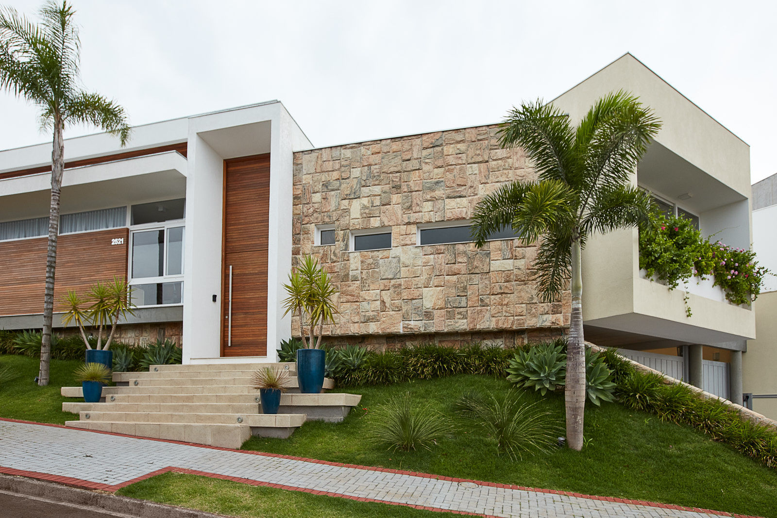 Fachada de casa contemporânea com pedra ferro e madeira + muro de