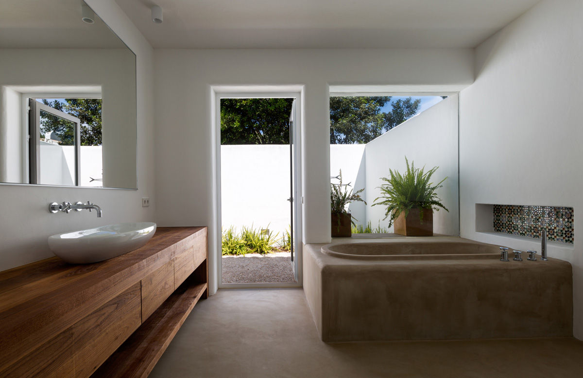 Bañera de hormigón y mueble de baño de madera con vistas al jardín. Alejandro Giménez Architects Baños mediterráneos Concreto