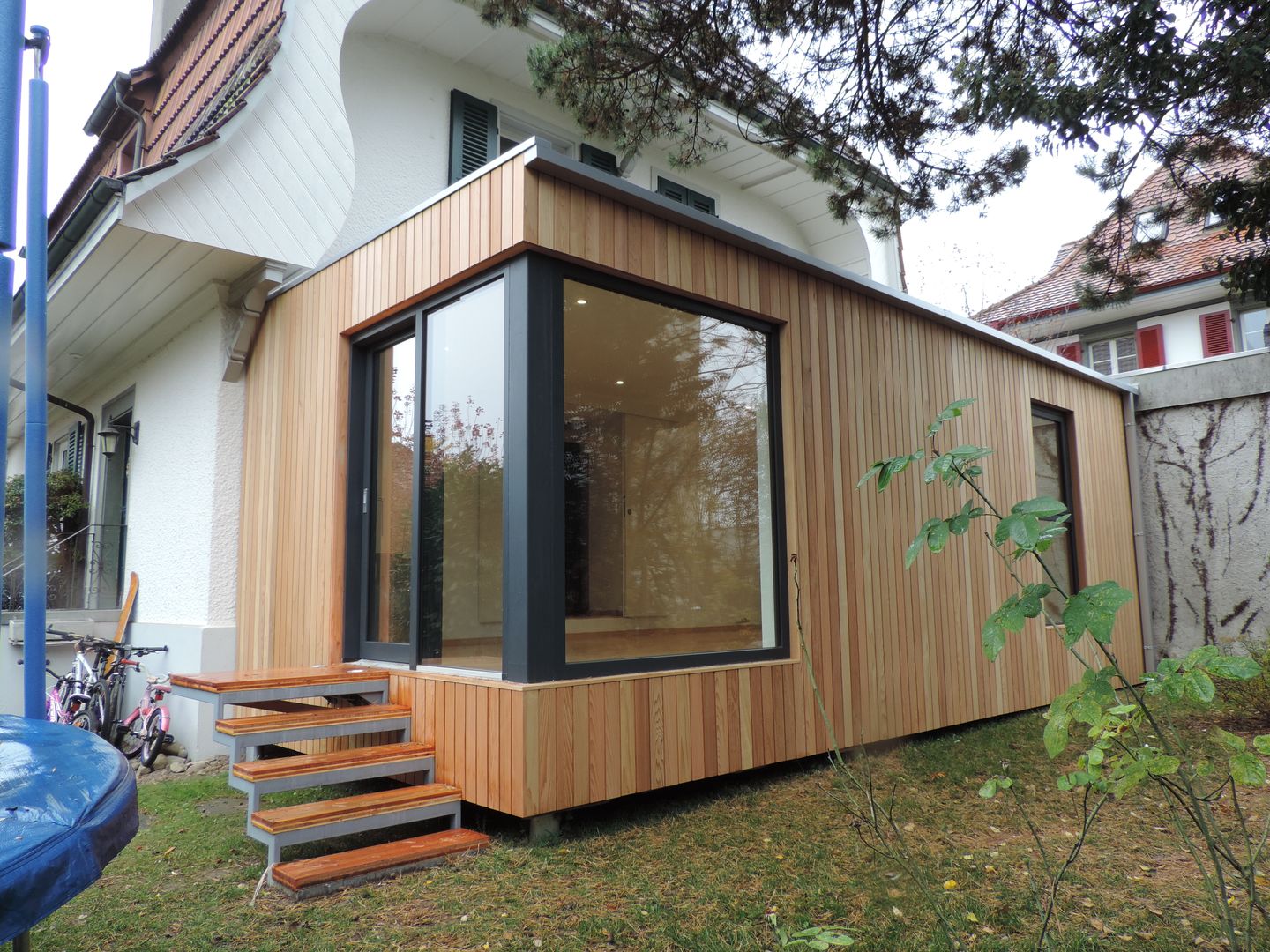 vista della vetrata d'angolo di ingresso homify Casa prefabbricata Legno Effetto legno ampliamento in legno,modulo abitativo,casa prefabbricata,esterno in legno,facciata in cedro,modulo ecologico