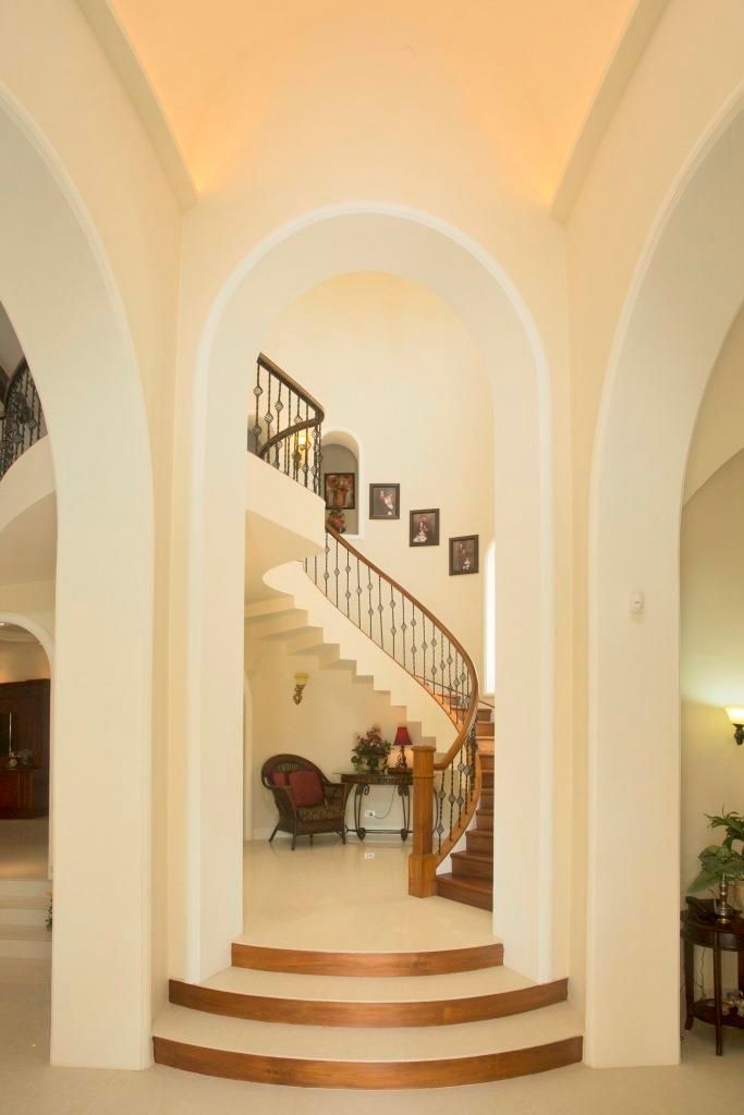 Double height arched entry to stair case room S Squared Architects Pvt Ltd. Stairs double height dining room, double height spaces, staircase design, curved stairs, circular stairs, spiral stairs, staircases, metal handrail design