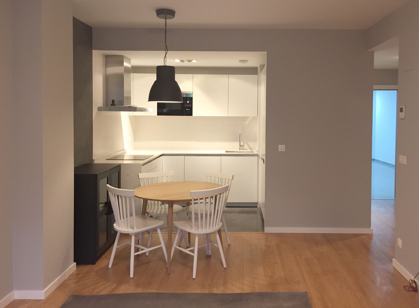 Cocina comedor con suelo laminado madera clara, pared gris claro con cocina blanca Muka Design Lab Cocinas a medida