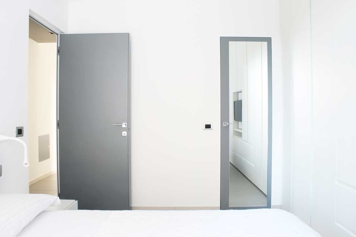 Camera da letto matrimoniale con porta a specchio per accesso al bagno Francesco Ruffa Architetto Camera da letto moderna