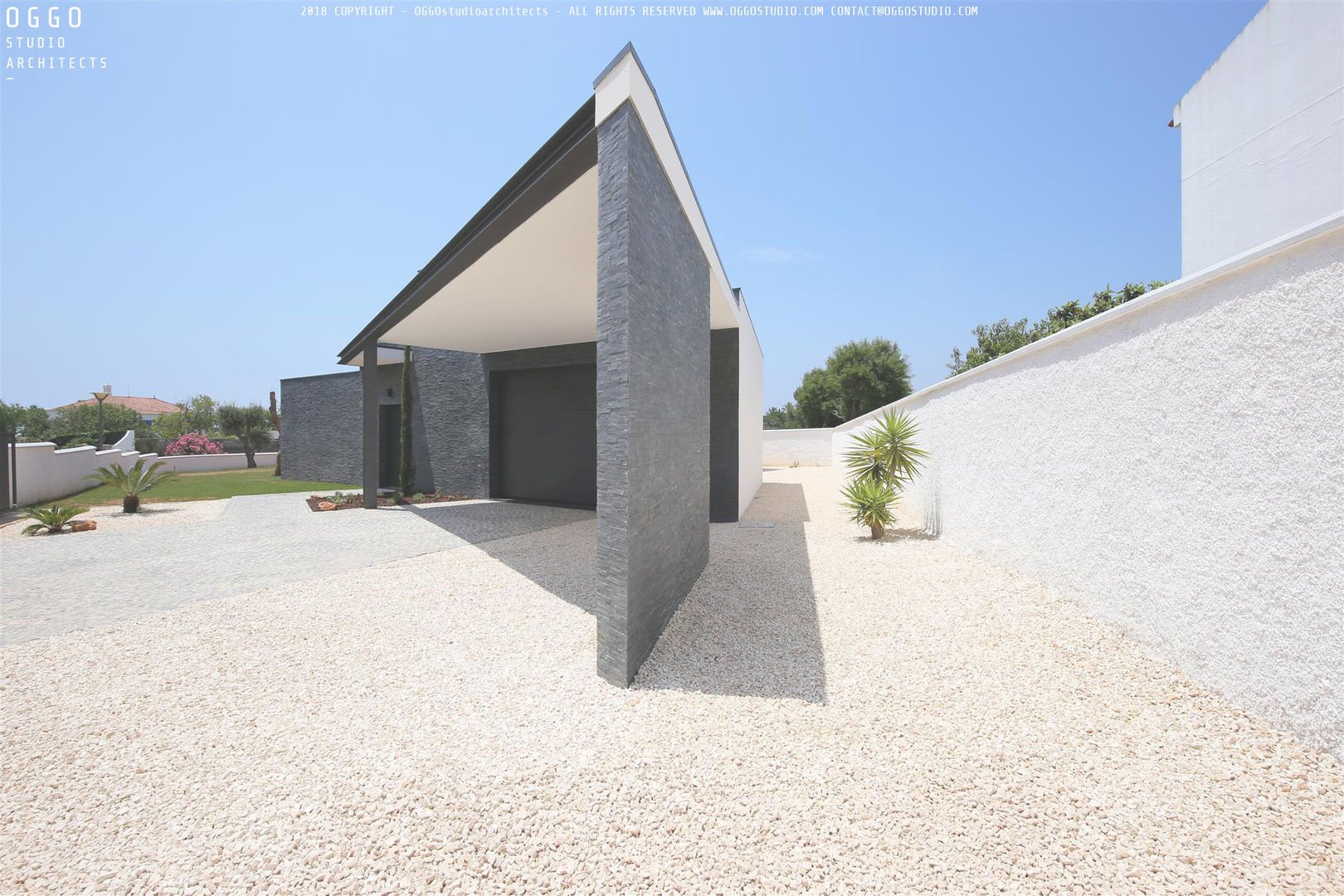 Entrada na moradia com 2 lugares de estacionamento cobertos OGGOstudioarchitects, unipessoal lda Casas minimalistas Quinta da Bela Vista,moradia,Algarve,casa,xisto,garagem