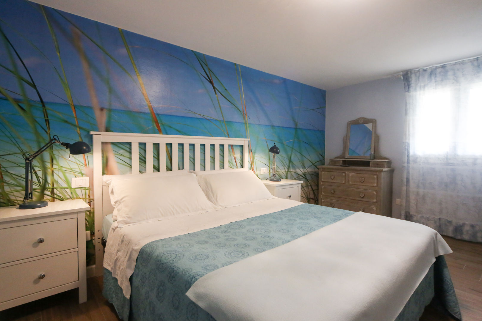 Mini seconda casa al mare: camera da letto con letto bianco e cassettiera con specchio Arch. Sara Pizzo – Studio 1881 Camera da letto piccola mini seconda casa al mare, progettazione online, carta da parati, letto Ikea bianco, lampada appoggio blu, soffitto basso