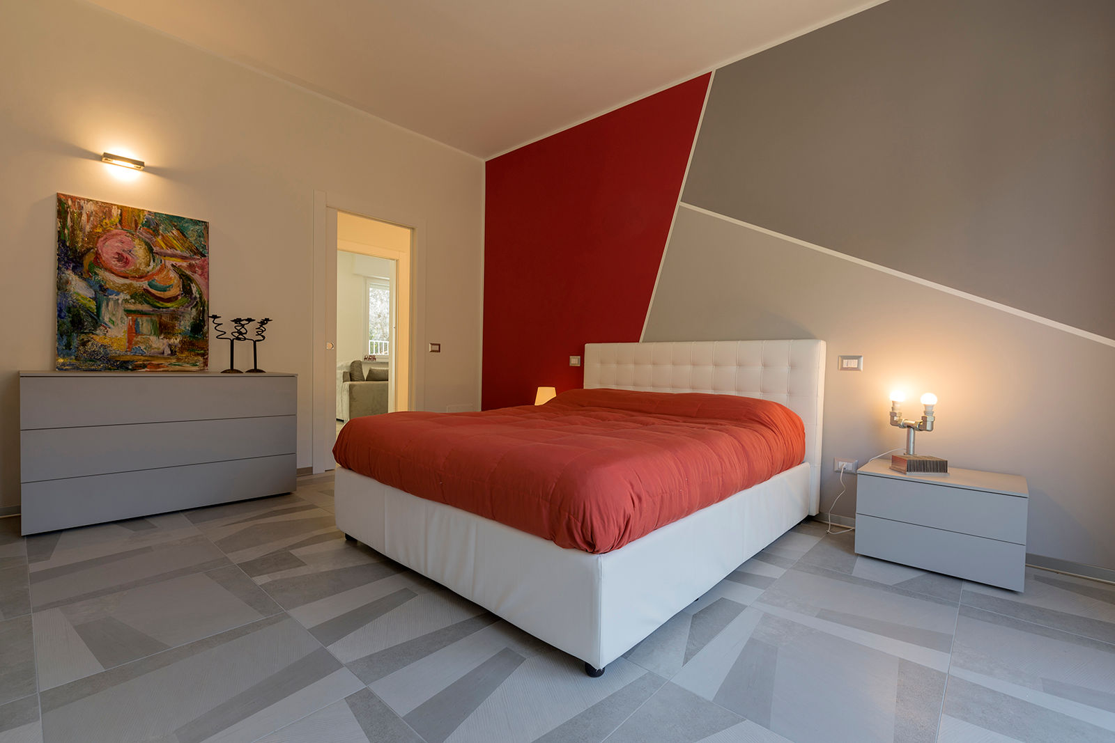 Camera matrimoniale Essestudioarch Camera da letto moderna pavimento in gres grigio bianco, pittura murale rossa e grigia, geometria, porta scorrevole, letto bianco